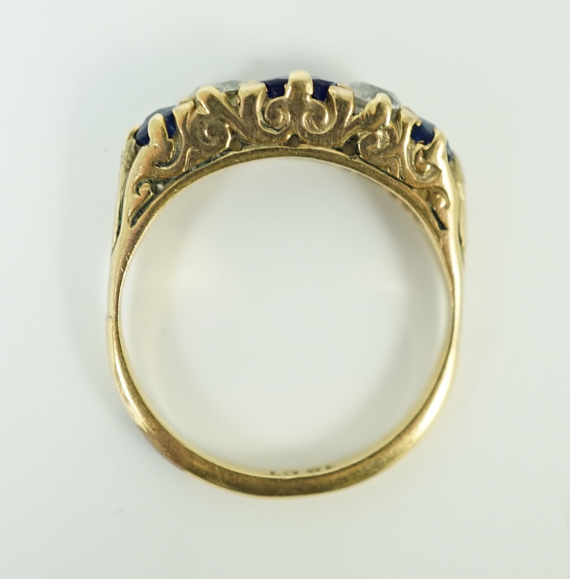 An 18ct gold, graduated three stone sapphire and two stone diamond set half hoop ring